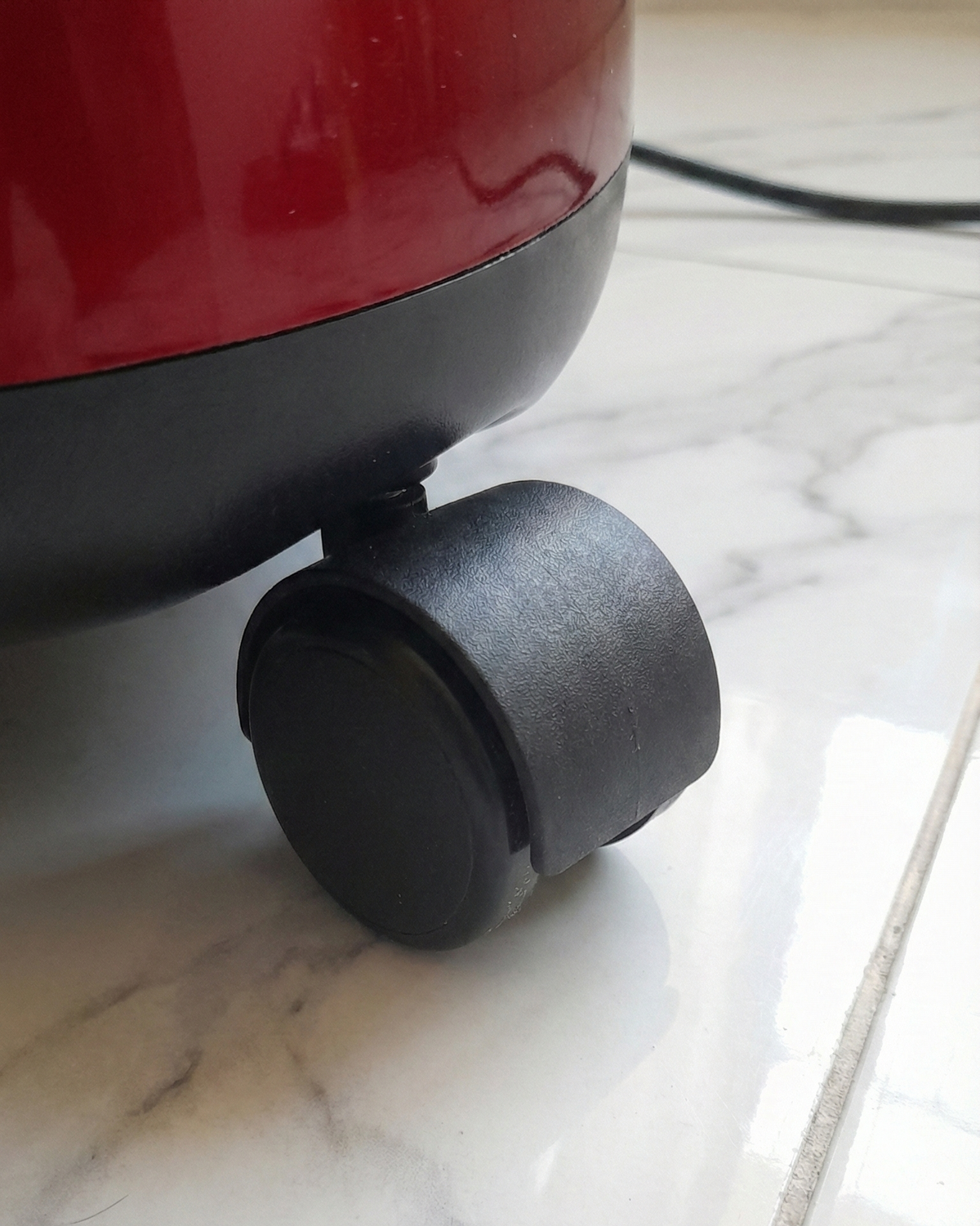 Black wheel on a red appliance base with a marble floor background