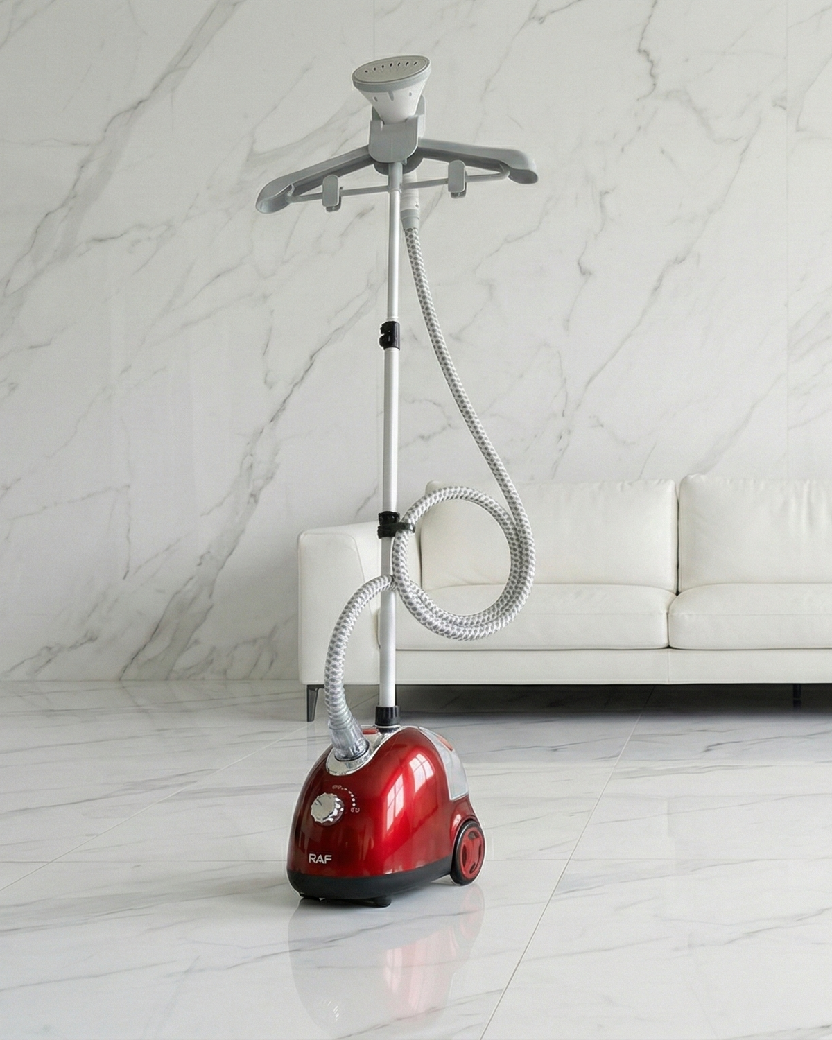 Red and gray garment steamer on a white floor with a white couch in the background