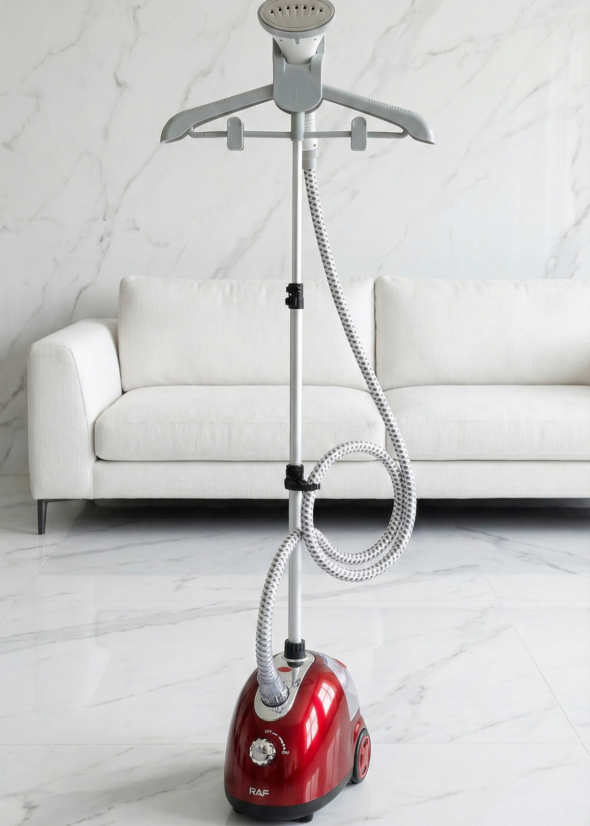Red and silver garment steamer on a white marble floor with a white sofa in the background.