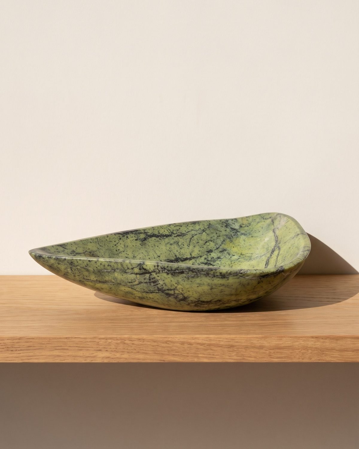 Lime Vein serpentine stone serving bowl on a sunlit wooden shelf