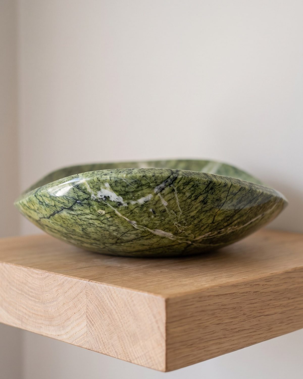 Spring Leaf serpentine stone serving bowl on a sunlit wooden shelf